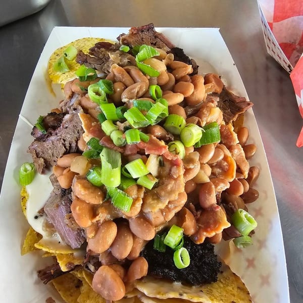 Poppy's Smokehouse BBQ nachos with pinto beans, brisket, cheese sauce, and green onions.