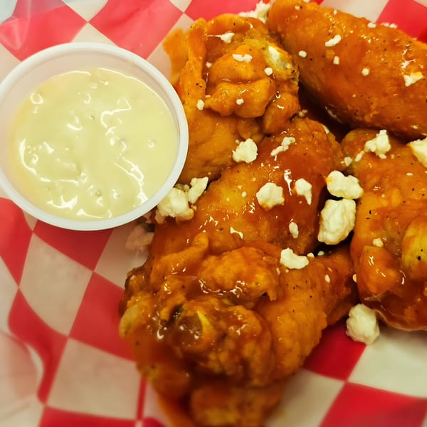 Poppy's Smokehouse buffalo wings with blue cheese crumbles and a side of ranch dressing.