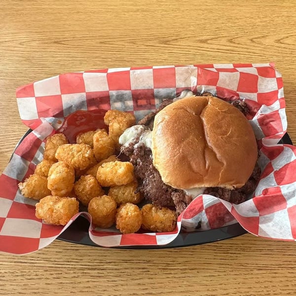 Poppy's Smokehouse diner burger with melted cheese and a side of crispy tater tots.